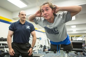 Student exercising at a gym with an instructor. 